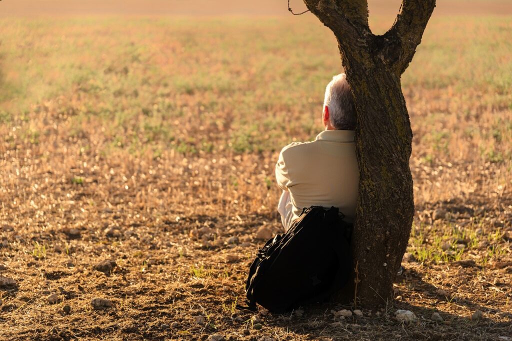 mindfulness in nature - man sitting by a tree on his own
